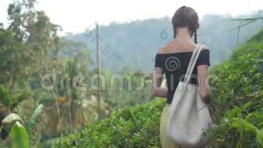年轻女子带着包走在小路上，闻着茶叶的味道